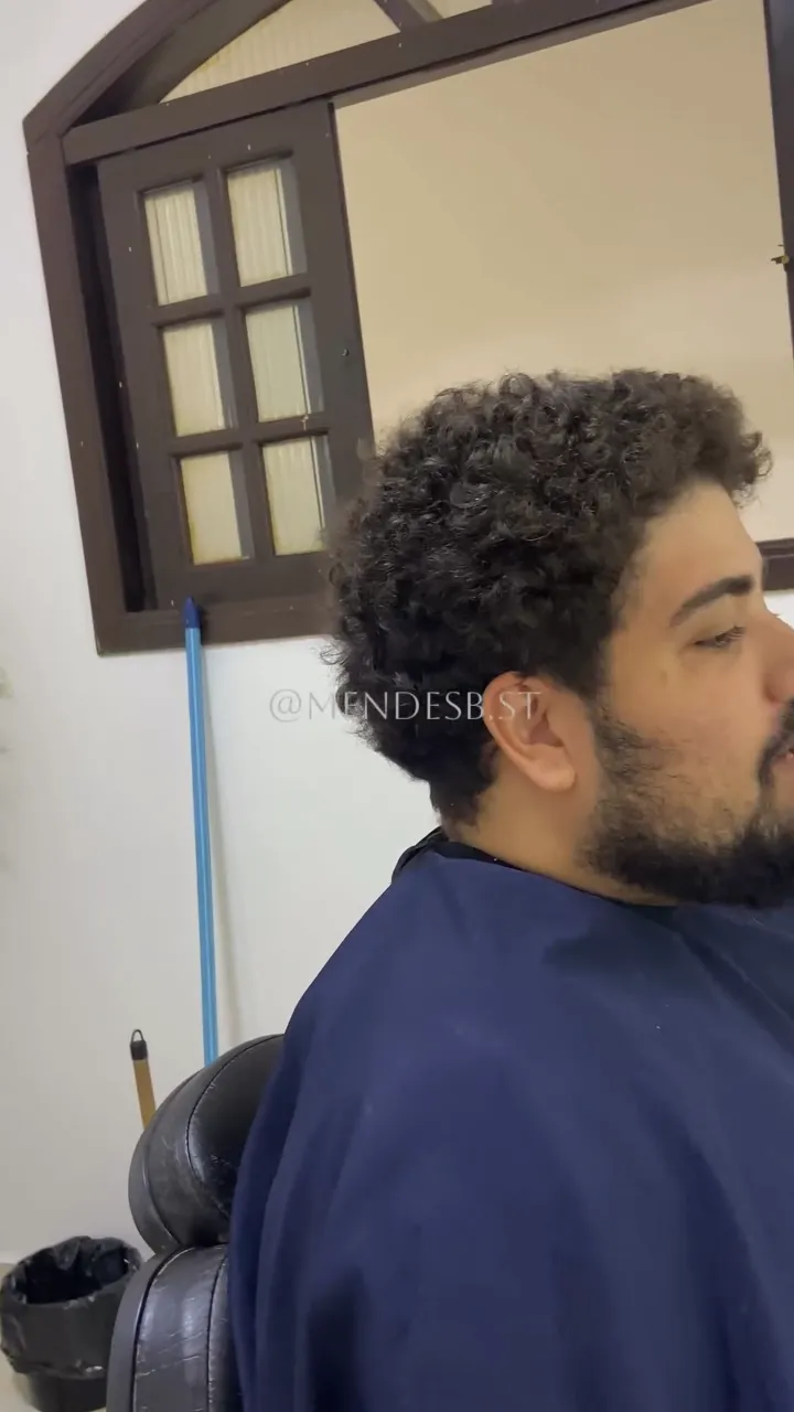 Antes: cliente de perfil com cabelo cacheado volumoso e barba cheia