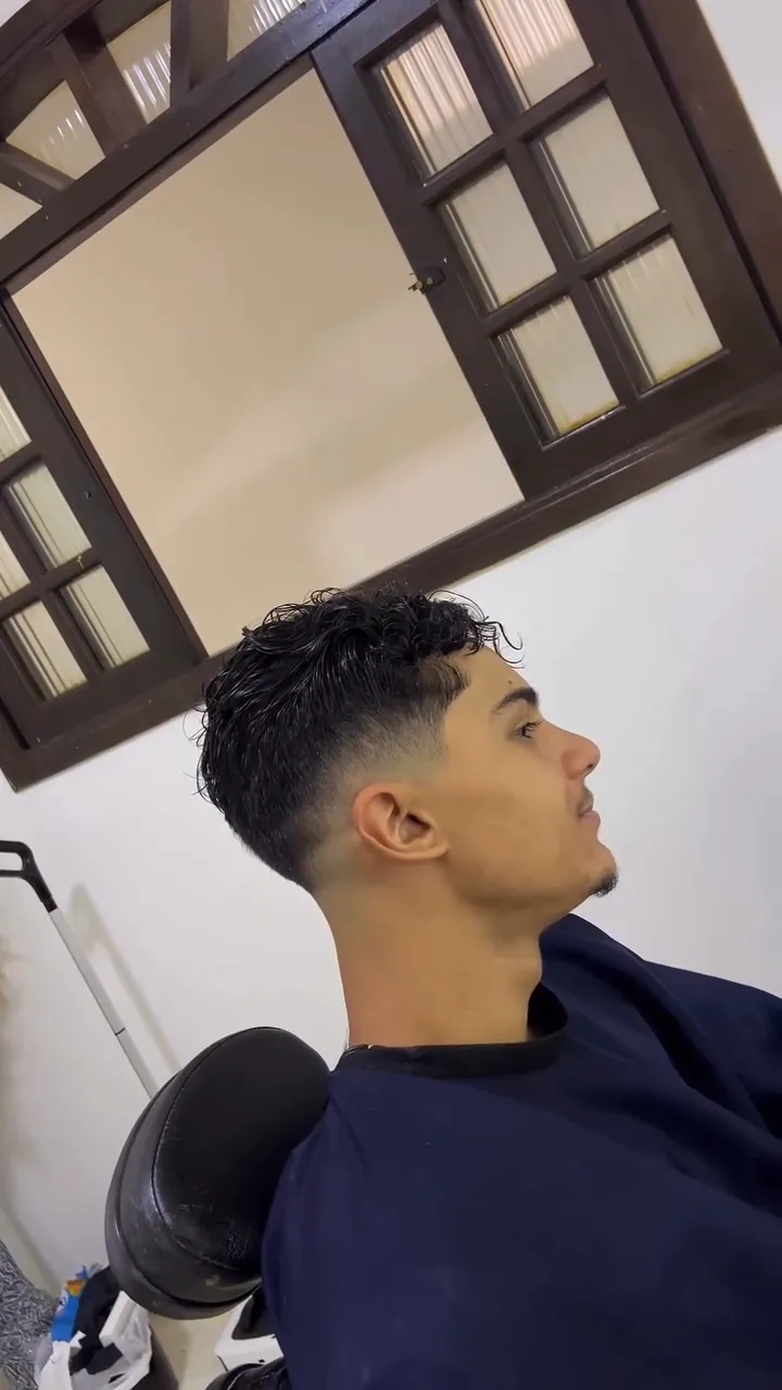 Cliente de perfil com cachos curtos em cima e degradê nas laterais
