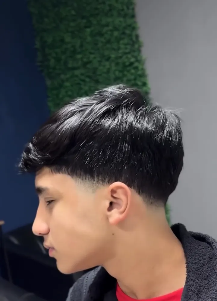 Jovem de perfil com franja lisa e texturizada e degradê baixo