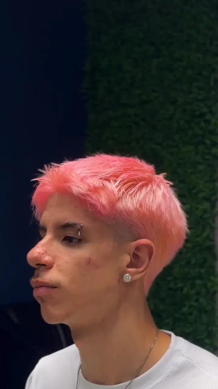 Cliente de perfil com o cabelo platinado e tingido de rosa, laterais baixas